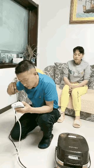 中年大哥家中修着插排，大嫂把他裤兜即将掉落的手机拿了过来看，大哥回头一看，老婆查