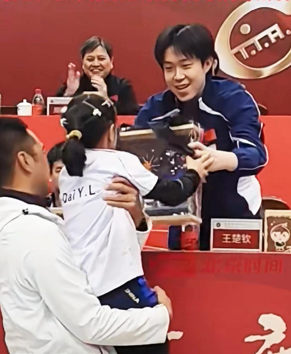 王楚钦收到9岁粉丝的礼物，赶紧起身双手接礼物，并握手感谢，就连后边的领导都