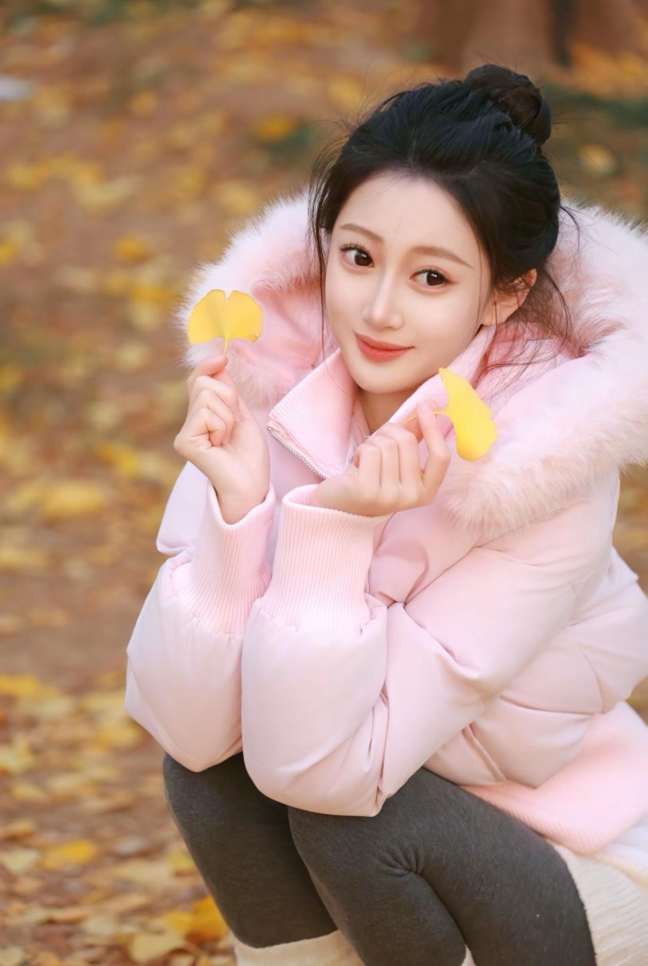 秋日暖阳下，少女轻抚落叶，甜美如画。