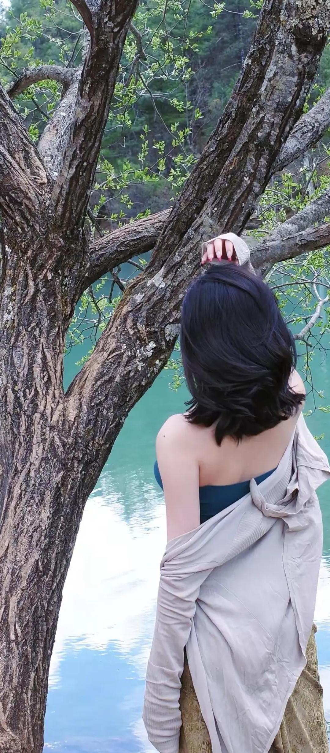 树影婆娑映碧波，佳人倚树思悠哉。