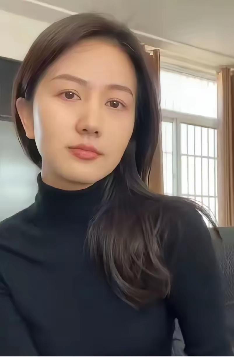 这姑娘穿着黑色高领毛衣，坐在窗边。