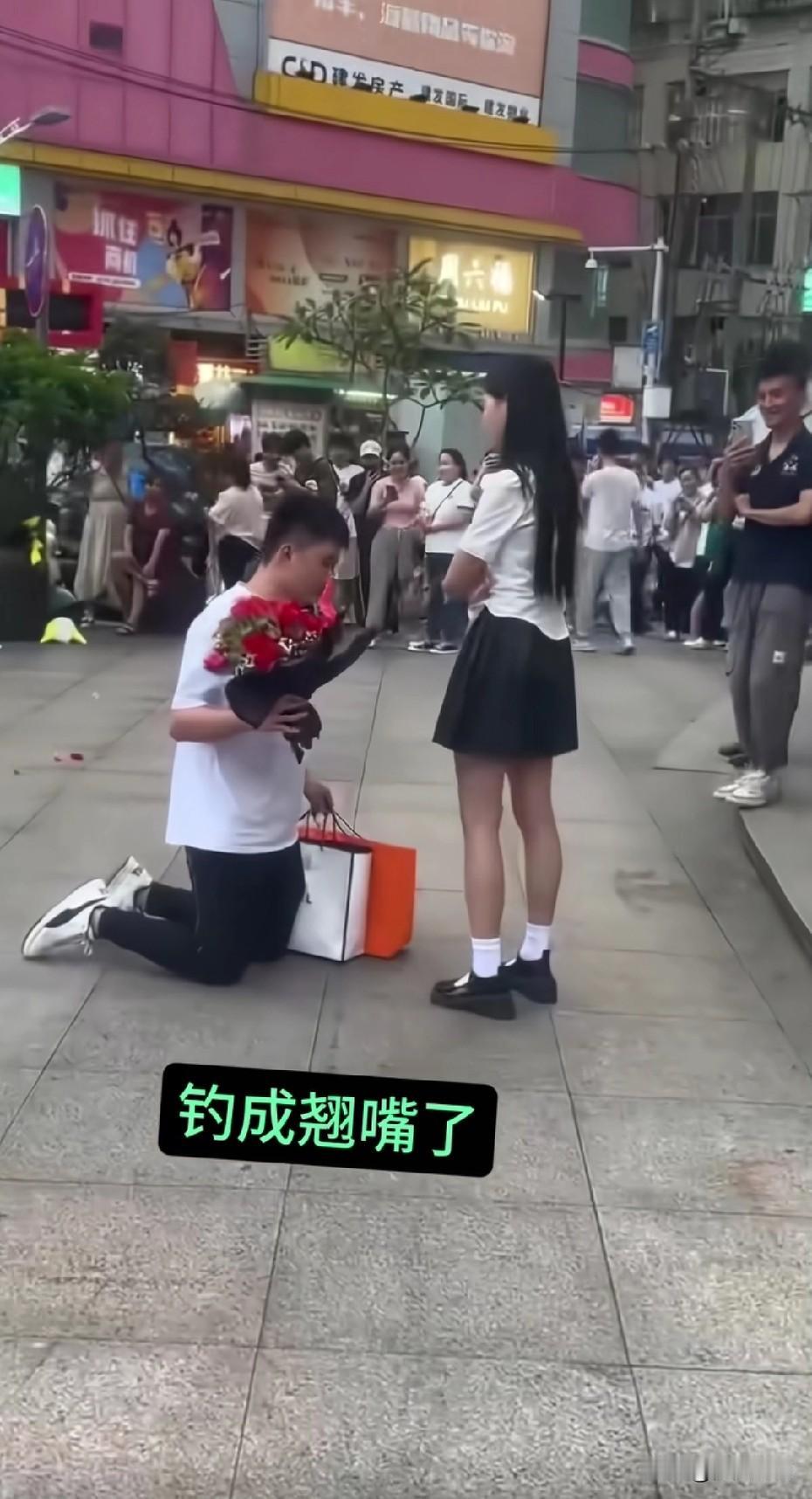 爱得太卑微了。男孩跪着递花，女孩一脸尴尬往后躲，周围在看笑话，他却像在演独角戏。