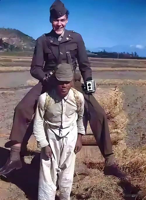 一名美国大兵骑着一名日本人拍照，他这是摆明了拿他找乐子。