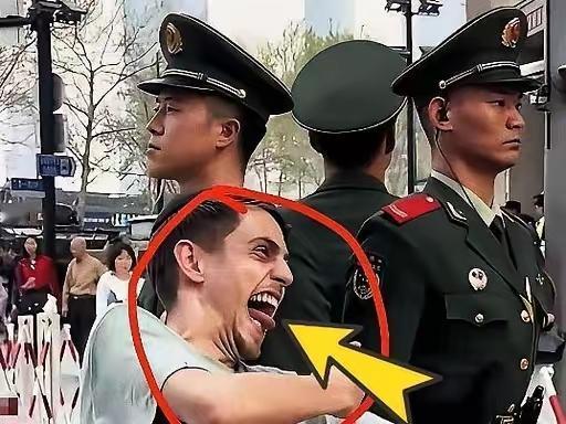 一名白人老外在上海外滩，对着笔直站岗的中国武警战士做鬼脸。他张大嘴、翻白眼，极尽