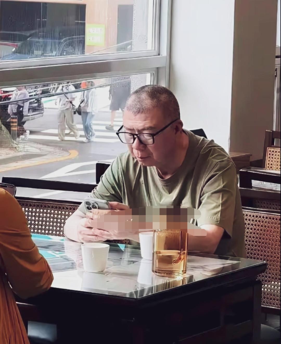 冯小刚独自前往韩国济州岛散心，没有带助理随从；他身着一件奢侈品橄榄绿色短袖，坐在