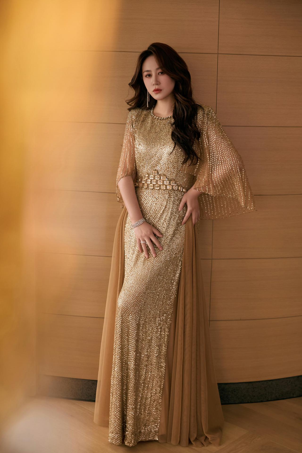 马丽，她身着JennyPackham金色亮片礼服，搭配斗篷袖、亮钻收腰腰带，还