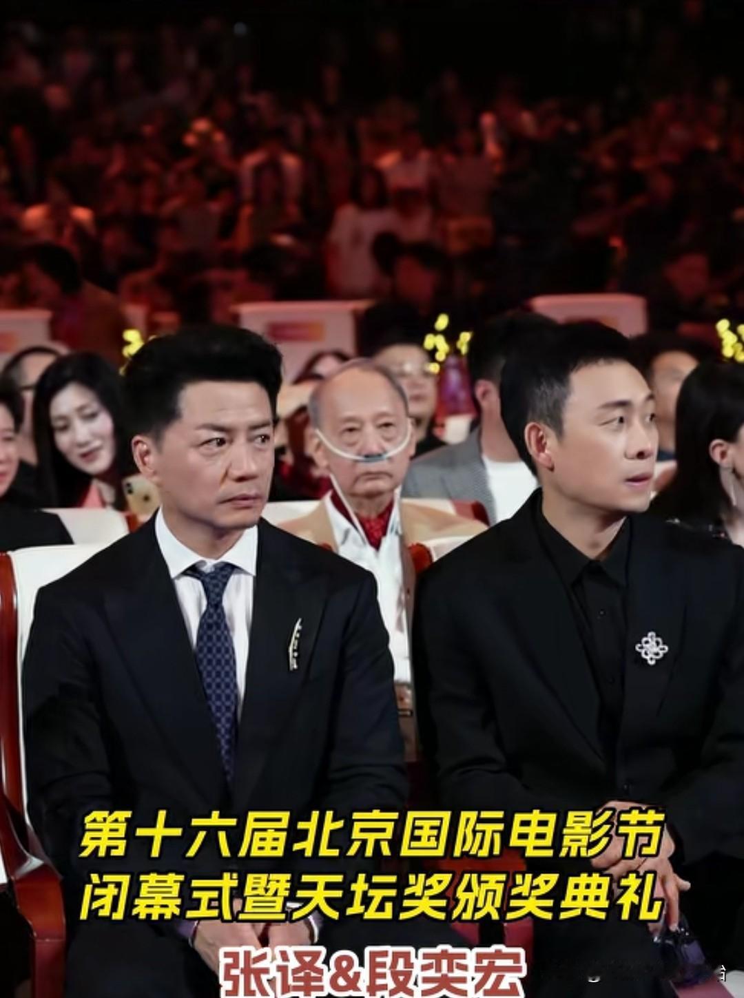 在第十六届北京国际电影节的现场，一一个十分感人的画面。在演员张译的后排，坐着一