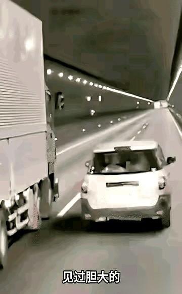 一头扎进隧道，那辆白色小车就疯了。油门一轰，贴着大货车巨大的轮胎，嗖一下就超了