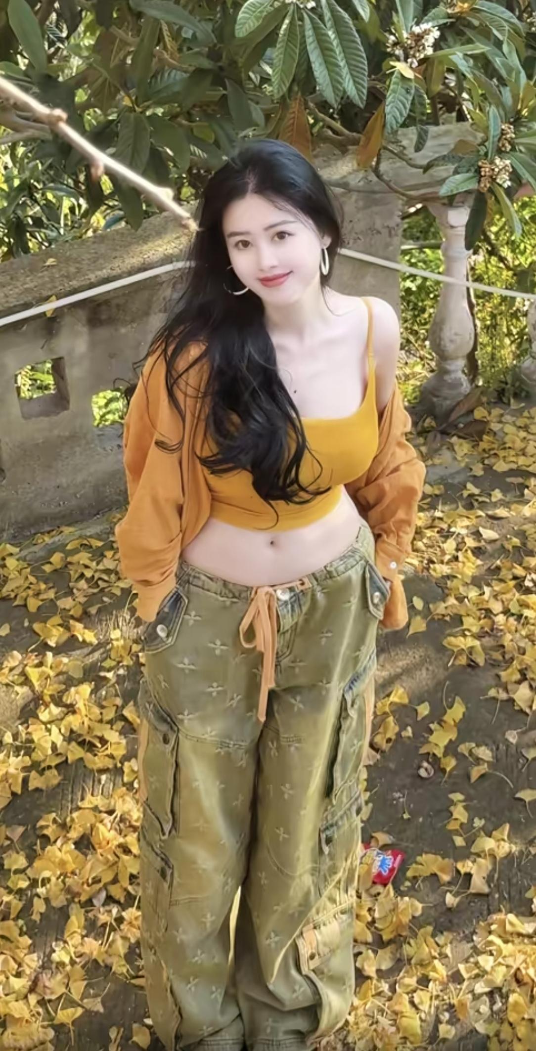 秋日暖阳下，她身着姜黄吊带与军绿工装裤，轻搭同色外套，低眸浅笑间，将随性慵懒的松