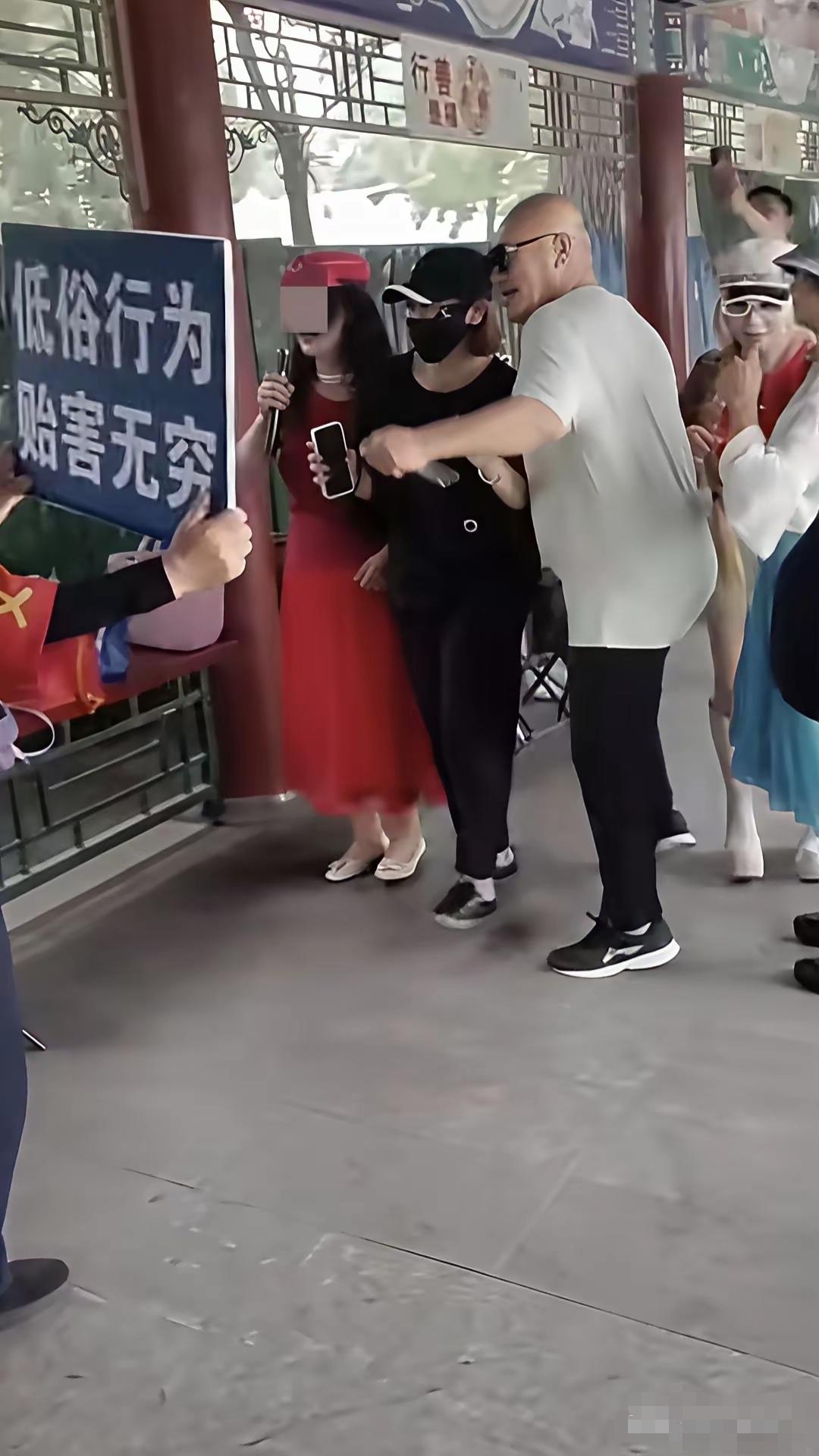 保安大哥举着牌子，看上面写的内容，估计对面的那帮人也是些“惯犯”了，公园内应该是