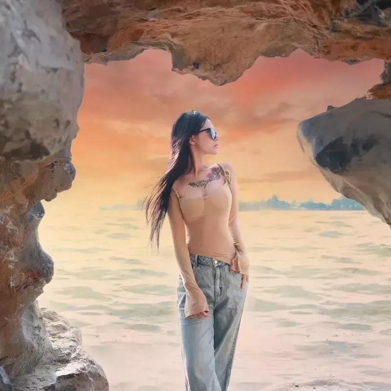 海边的岩石洞里，一位时尚女孩眺望远方，海天一色，美不胜收！海边度假女孩海边游玩