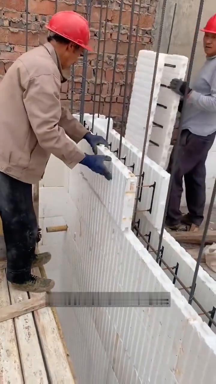 泡沫块建房。大家注意看，工人正将泡沫模块穿过钢筋，像搭积木似的一块块拼起来。好