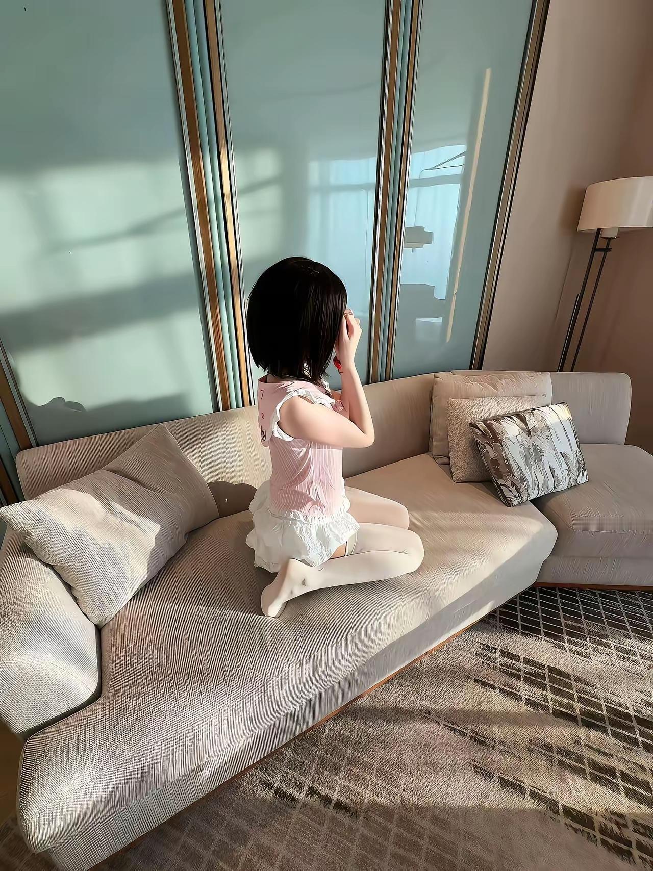 阳光洒进来的午后，小女孩坐在沙发上，静静地享受着宁静时光。白丝