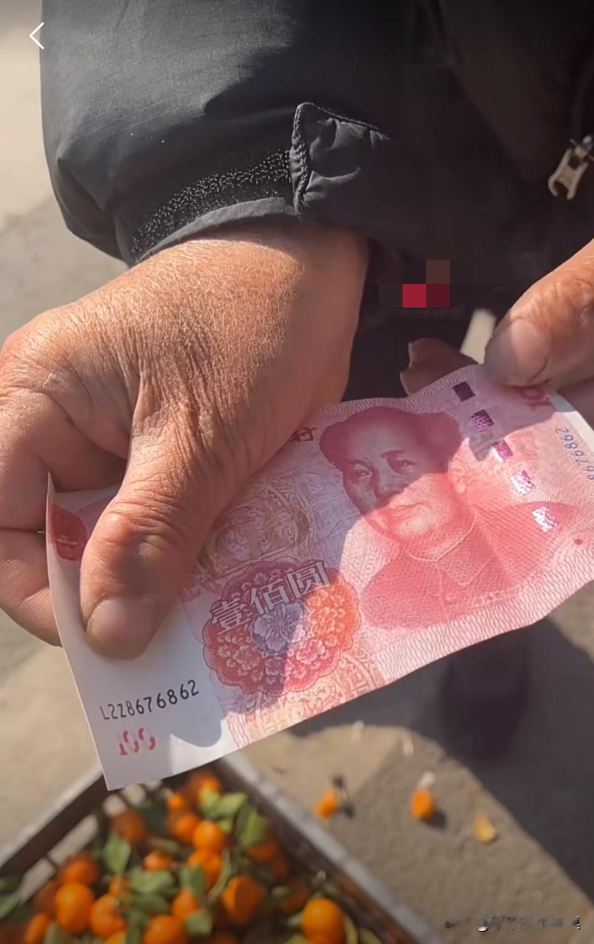 老人卖橘子，收到一张一百块的假钱，老人气的浑身发抖。老人一天也卖不了一百块钱的