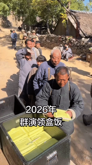 这些群众演员正在排队领取盒饭。看起来这还是一个抗日剧的剧组？其实当群演拍一天