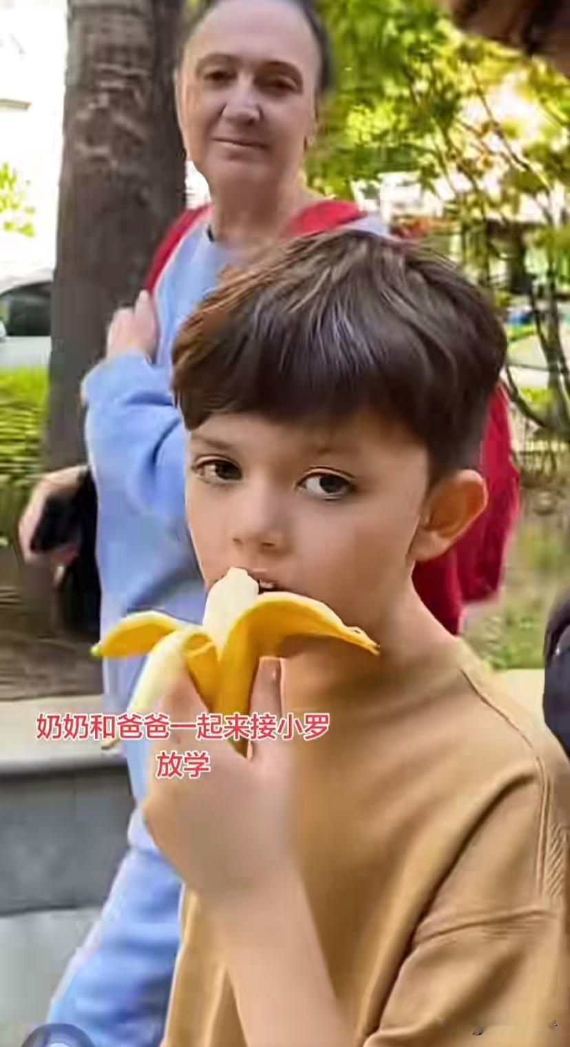 罗兰多和妈妈一起来接小宝放学了，小宝边吃着香蕉边和爸爸对话，英语方面可提高了不少