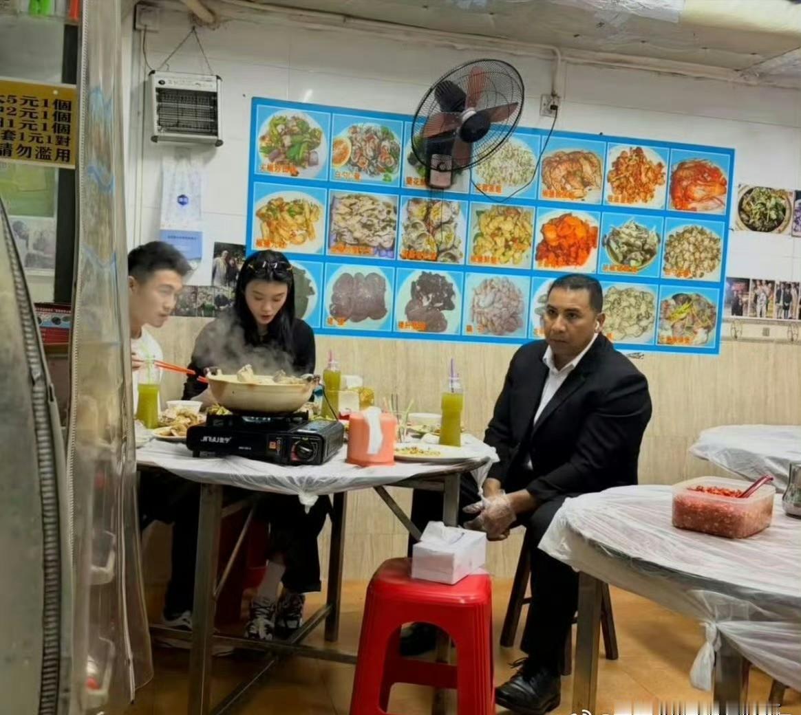 何猷君坐在苍蝇馆子的塑料凳子上吃粉，地上落着保安刚带进来的灰和汗。帮他铺这个场