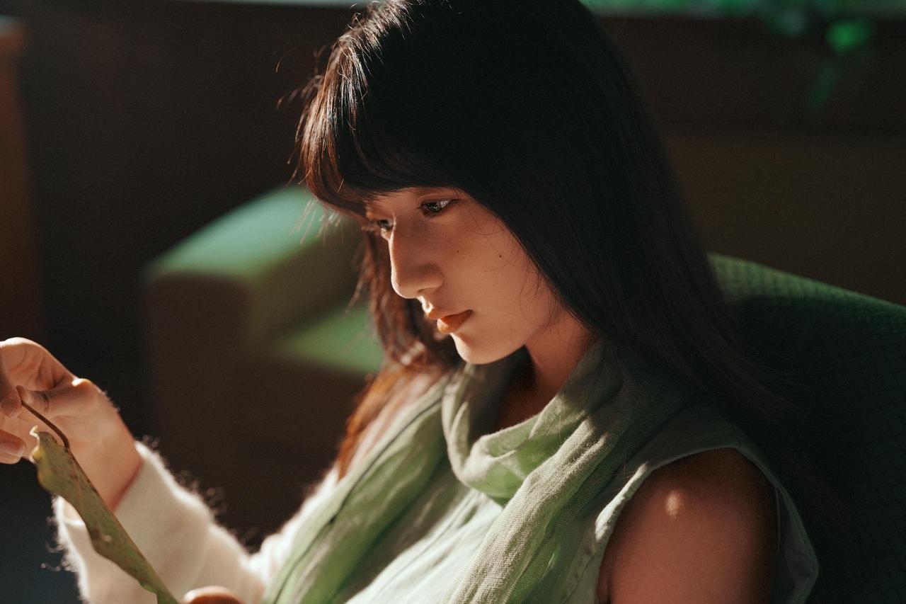 这张全身人像将人物置于室内与户外的过渡空间，木质家具的沉稳与花卉的柔美形成对比，