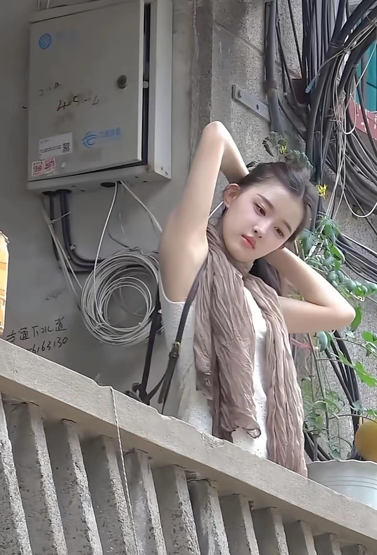 走廊的光线柔和地落在小思思身上，她抬手整理头发的瞬间，侧脸线条温婉舒展。都说她长