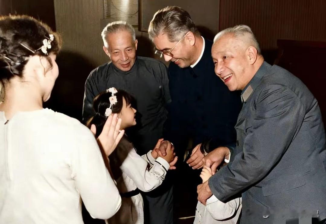 这张照片定格了温馨一幕：粟裕、荣毅仁、陈丕显三位长辈，正笑着与孩子们互动。右侧