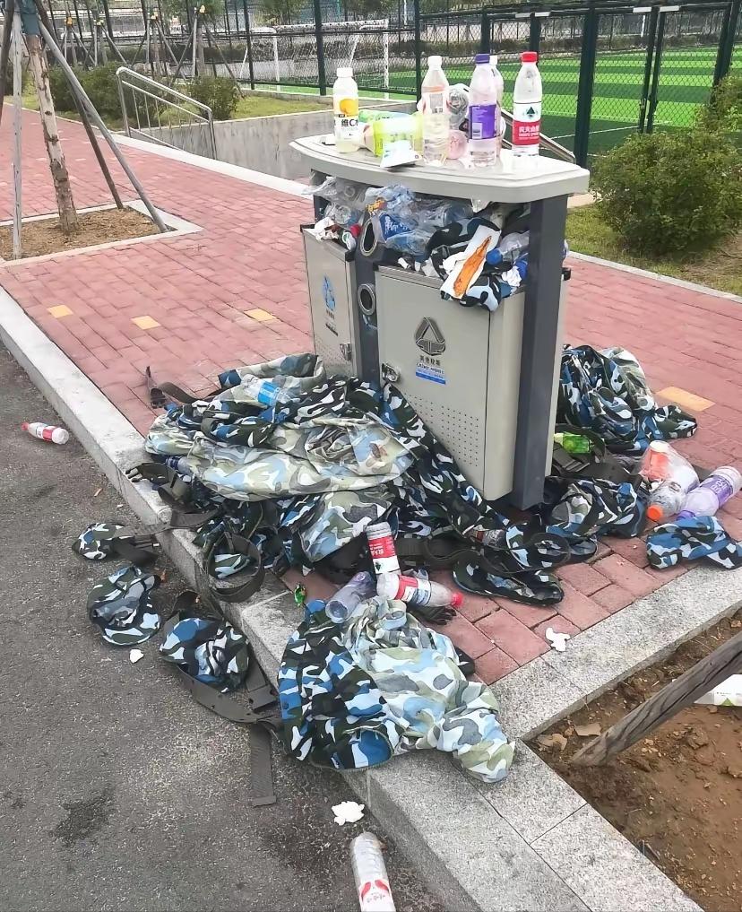 军训刚结束，大一新生就把全新的迷彩军训服丢进了垃圾箱。一个从乡下来的大一女生看着