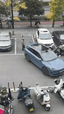 见过用身体占车位的，可没见过这么聪明的车主！一女子把包往地上一放，人往空车位中间