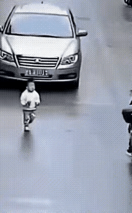 小小只不知危险，大模大样地走在马路上，一辆灰色轿车开过来没刹车，电瓶车小哥斜刺里