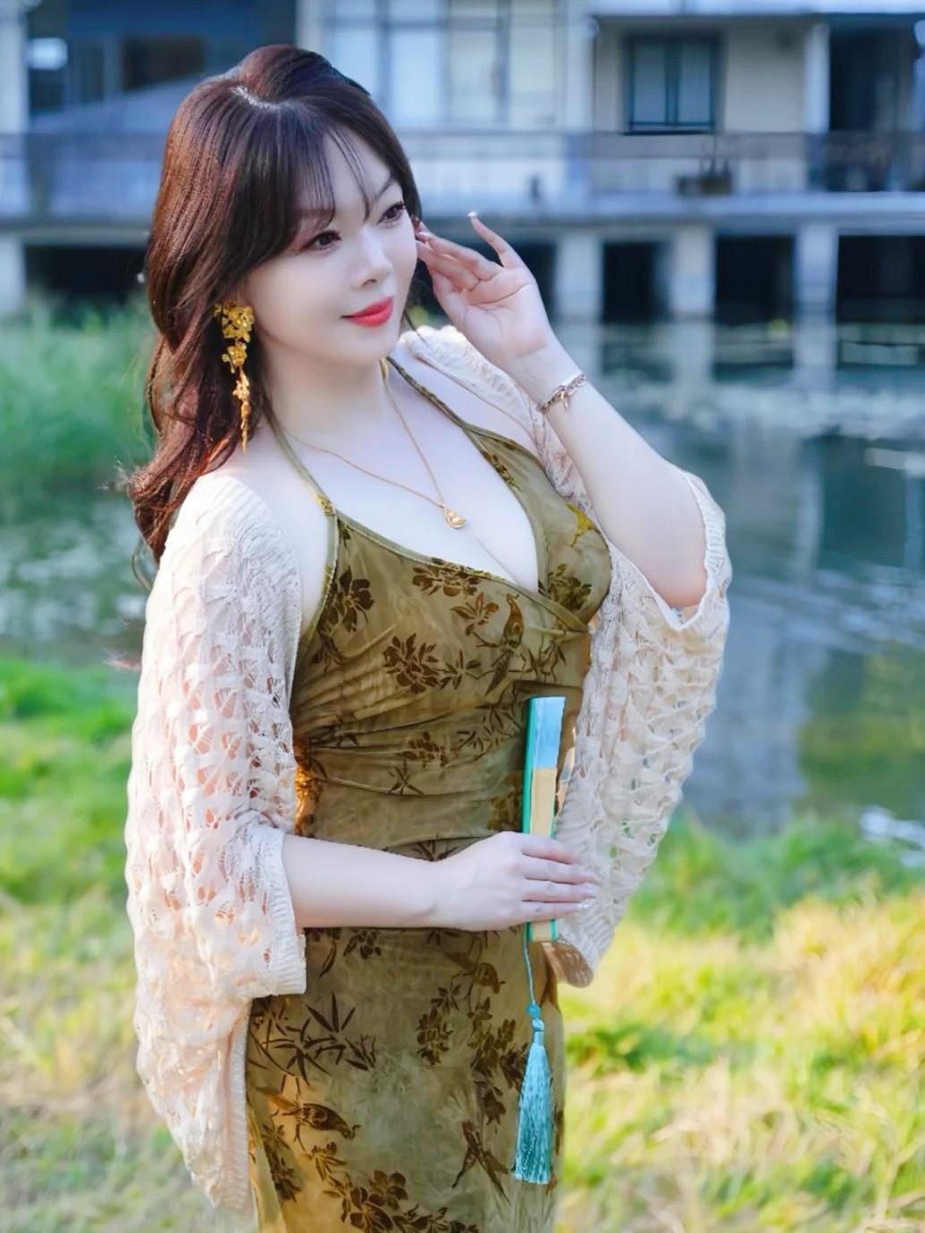 《苔绿罗裙》苔绿罗裙覆软纱，香风拂袖胜桃花。手持轻扇凝春态，立向溪桥沐晚霞。