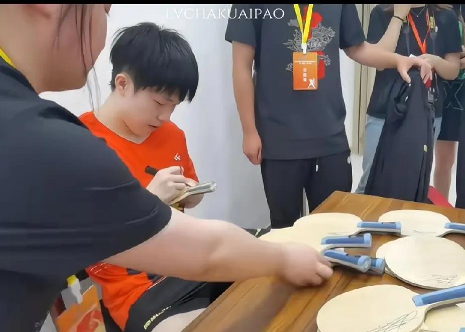 被王楚钦的真诚狠狠圈粉刷视频看到王楚钦专注签名的画面，桌上堆满了乒乓球拍，他一