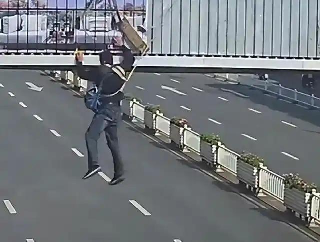 江苏淮安一名男子在天桥安装广告牌时，安全锁扣突然脱落，被安全绳挂在半空，像风筝一