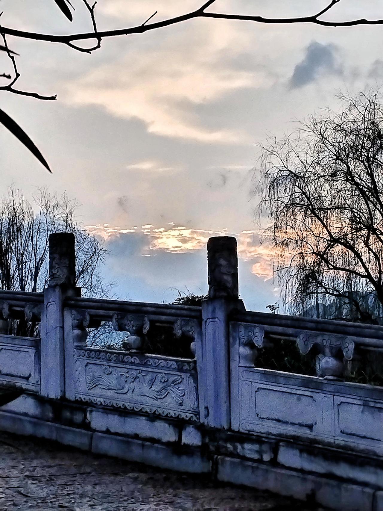 公园慢步，景色正好，古桥静卧，云霞映照。