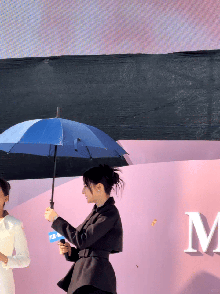 《迪丽热巴撑伞：把温柔给别人，也留份暖意给自己》粉色背景前那把蓝伞，是迪丽