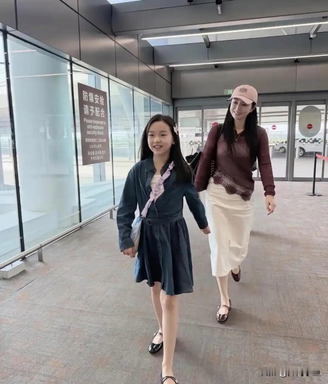 董璇带女儿小酒窝现身机场！一身休闲穿搭，酒红色镂空针织上衣搭配米白色半身长裙