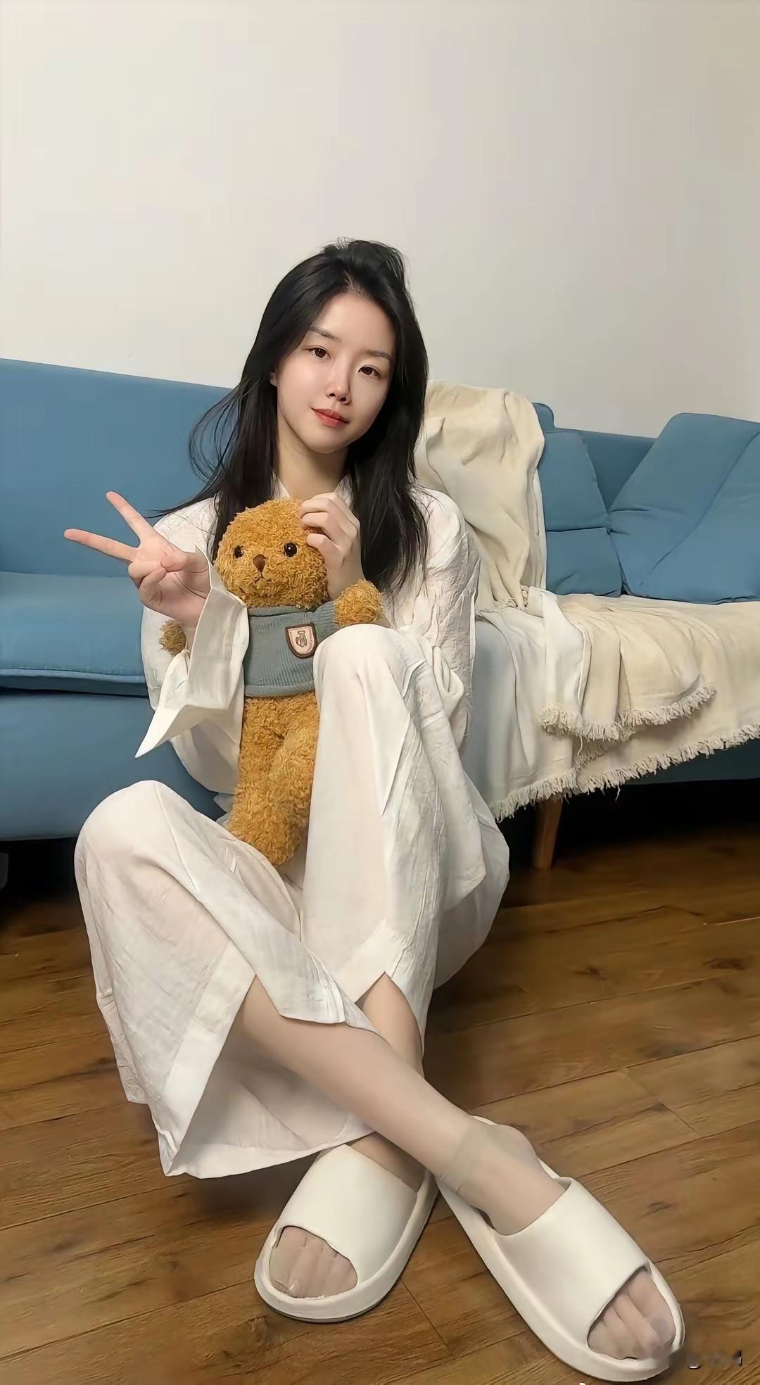 看到小姐姐坐在沙发上，抱着小熊玩偶比V字手势，这画面简直太治愈了。就像千库网上那