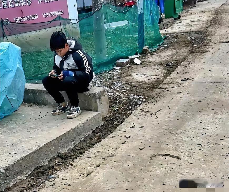 每天上班路过路口，看到一个小男孩缩坐在门口打游戏。他才十二岁，本该在学校读书的年
