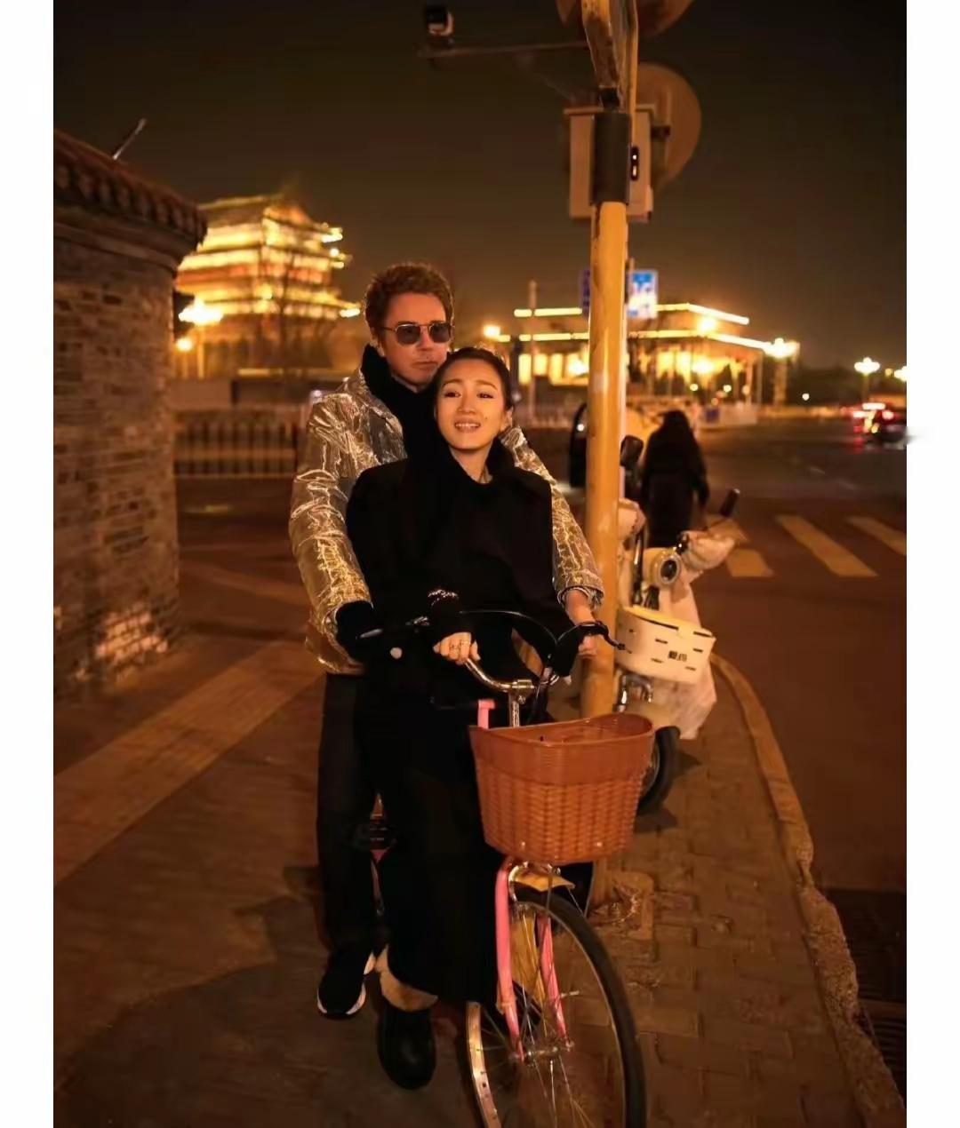 事情发生在马路牙子边上，巩俐坐在外国老公的自行车上笑。他们俩要是穷得只剩一辆自行