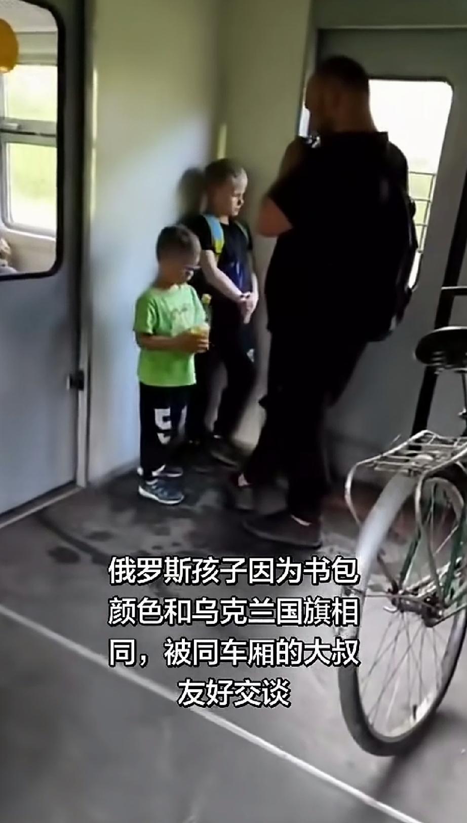 在火车上，一个俄罗斯小朋友背着颜色和乌克兰国旗有点相似的书包，被一位俄罗斯大叔看
