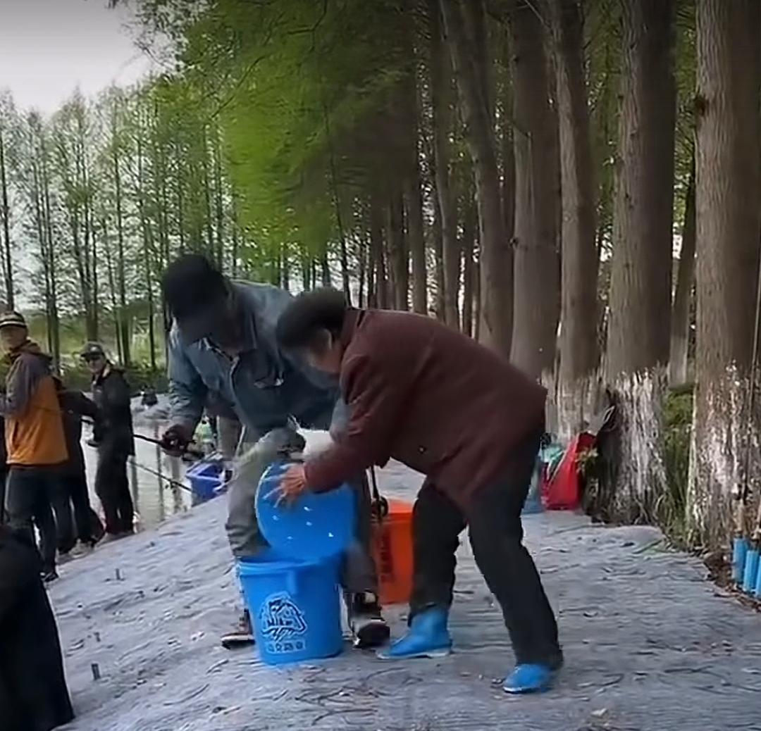 厉害了,大妈!男子在河边钓上一条鱼,放进桶里还没捂热乎呢。一大妈直接冲过来把桶