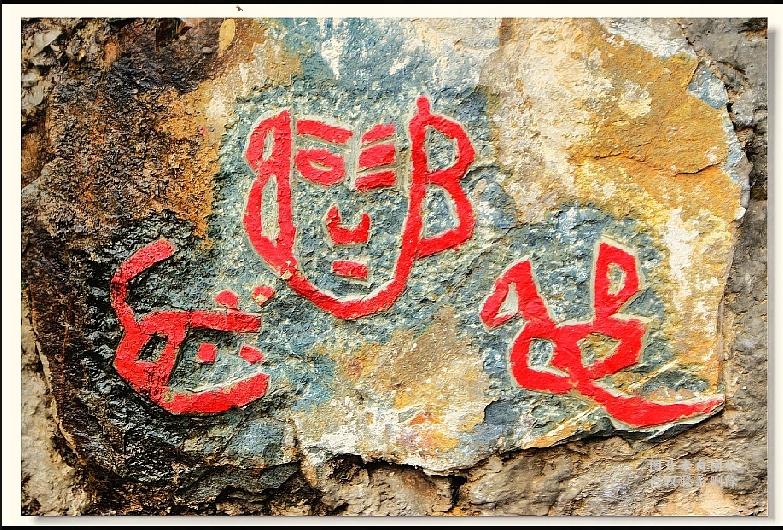 山里石刻古文字，形似人脸没人能看懂山里石头上刻着这两个红色古文字，造型特别奇