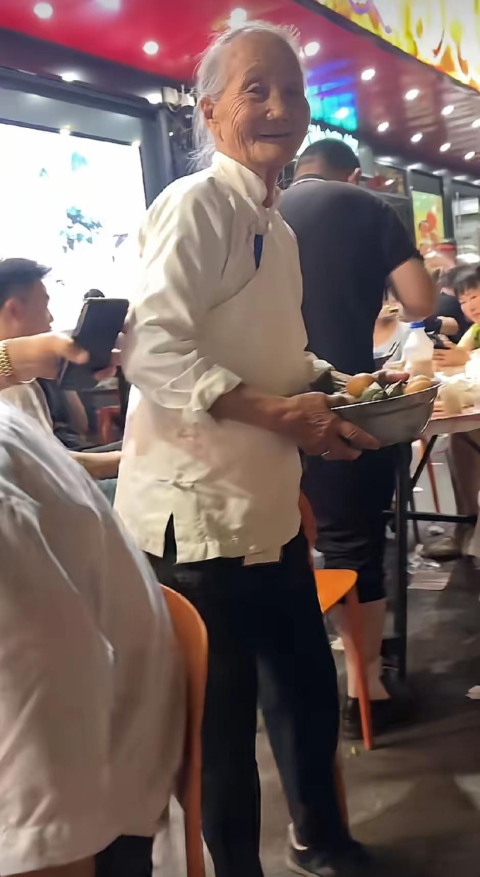 6月15日，河南信阳固始县的夜市灯火如常，喧闹中却因一位银发老人悄然静止——她身