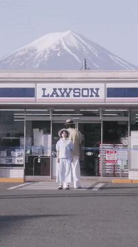 日本富士山下，一对中国小情侣在便利店门前打卡跳舞，路过游客互相礼让协助完成拍摄。