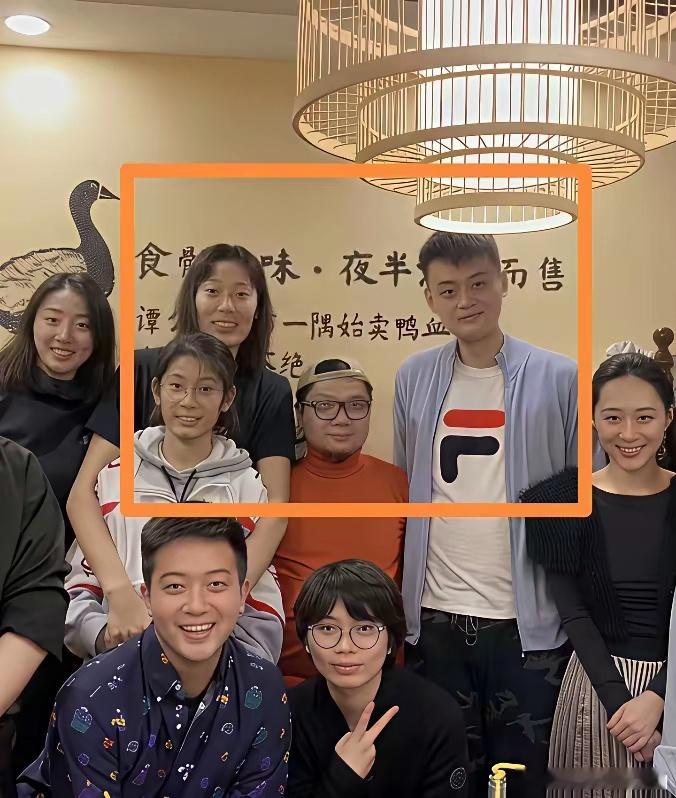 程青松这张合影照片，他到底是和众多朋友一起站着合影呢？还是他在后面单独坐着合影？