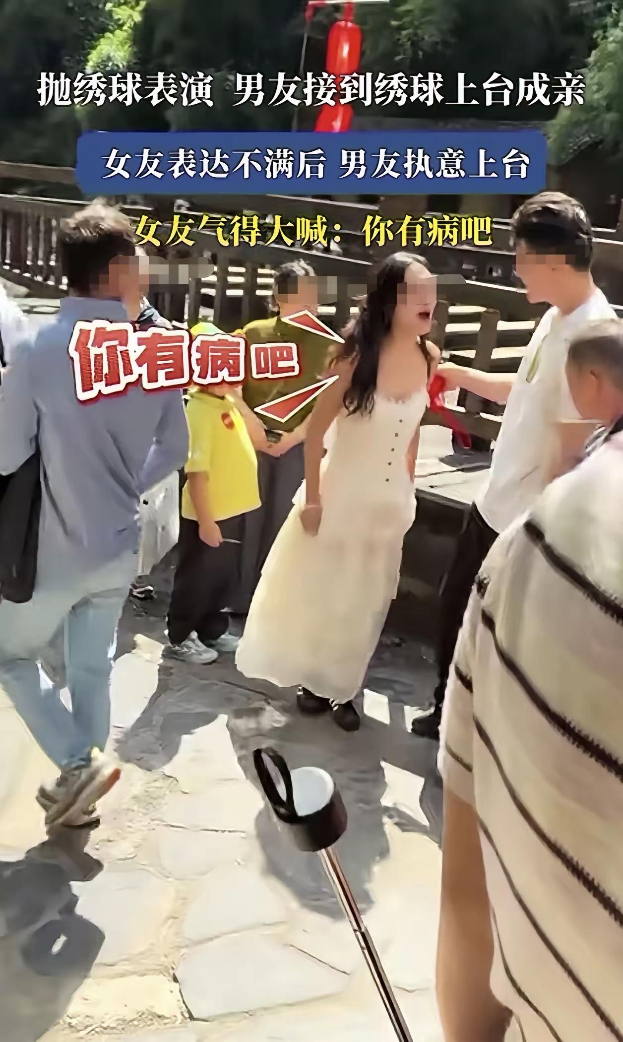 景区正在进行抛绣球民俗表演，一名男子意外接到绣球。女友当场就流露出不满，明确拦着