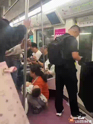 一辆地铁上，一位阿姨抱着睡熟的孩子蹲在地上，她的手里还拿着东西，但却没有一个人给