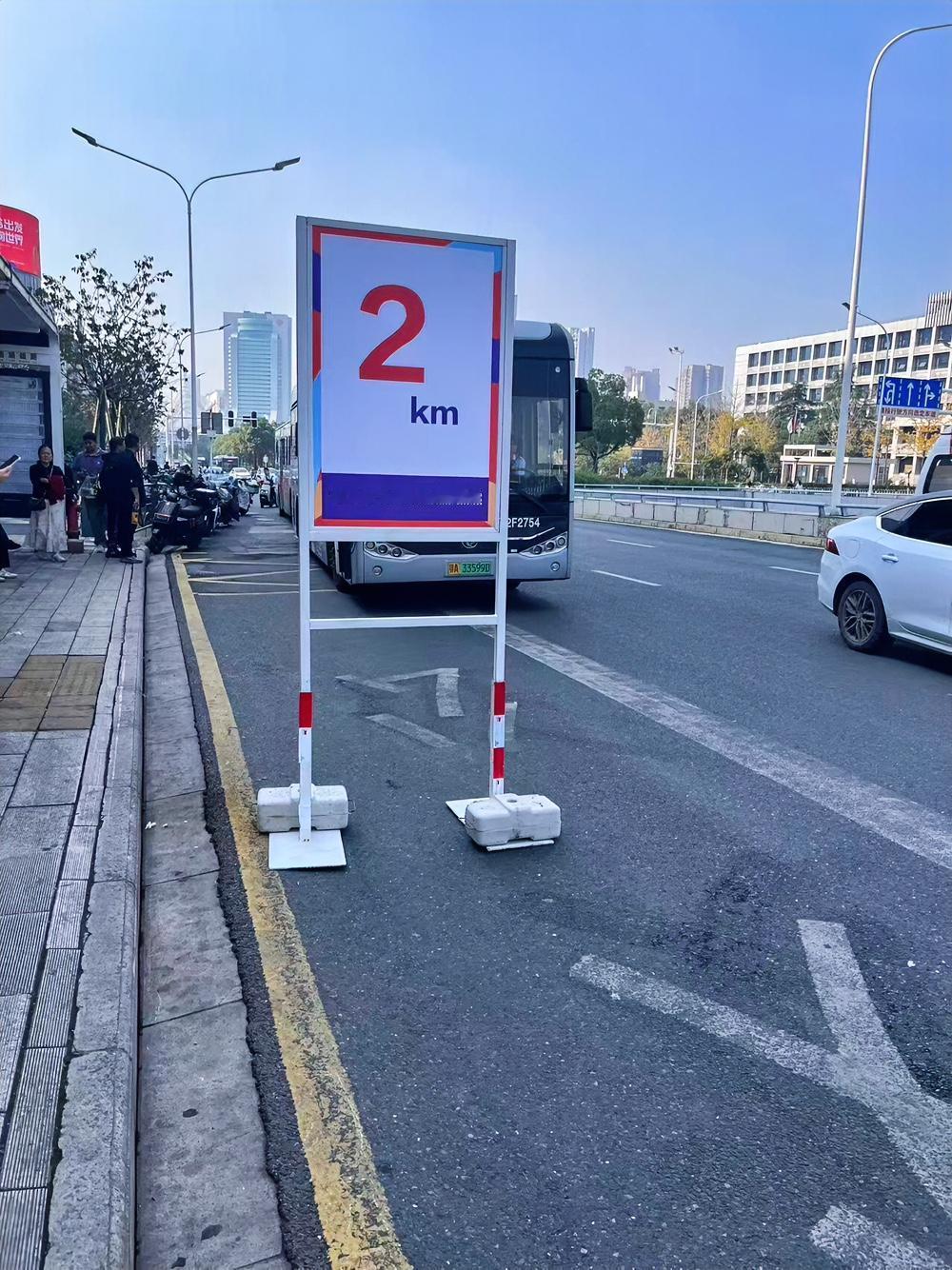 今天武汉马拉松这阵仗可太大了！出门就瞅见路边立着“2km”的指示牌，马路直接