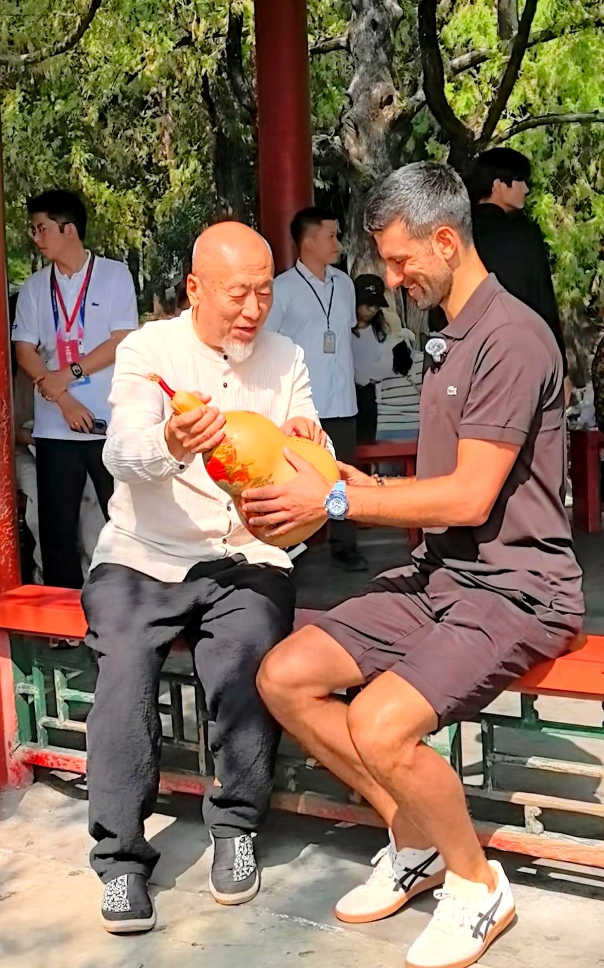 德约科维奇在颐和园捧着个大葫芦，对面站着个滔滔不绝的北京大爷。大爷拿着手里的“法器”，一口中文娓娓道