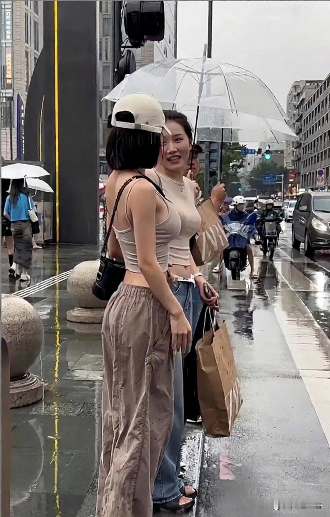 下雨天街头拍到这一幕，真是又好笑又有点微妙——刚下过雨，地面还湿漉漉的，两位