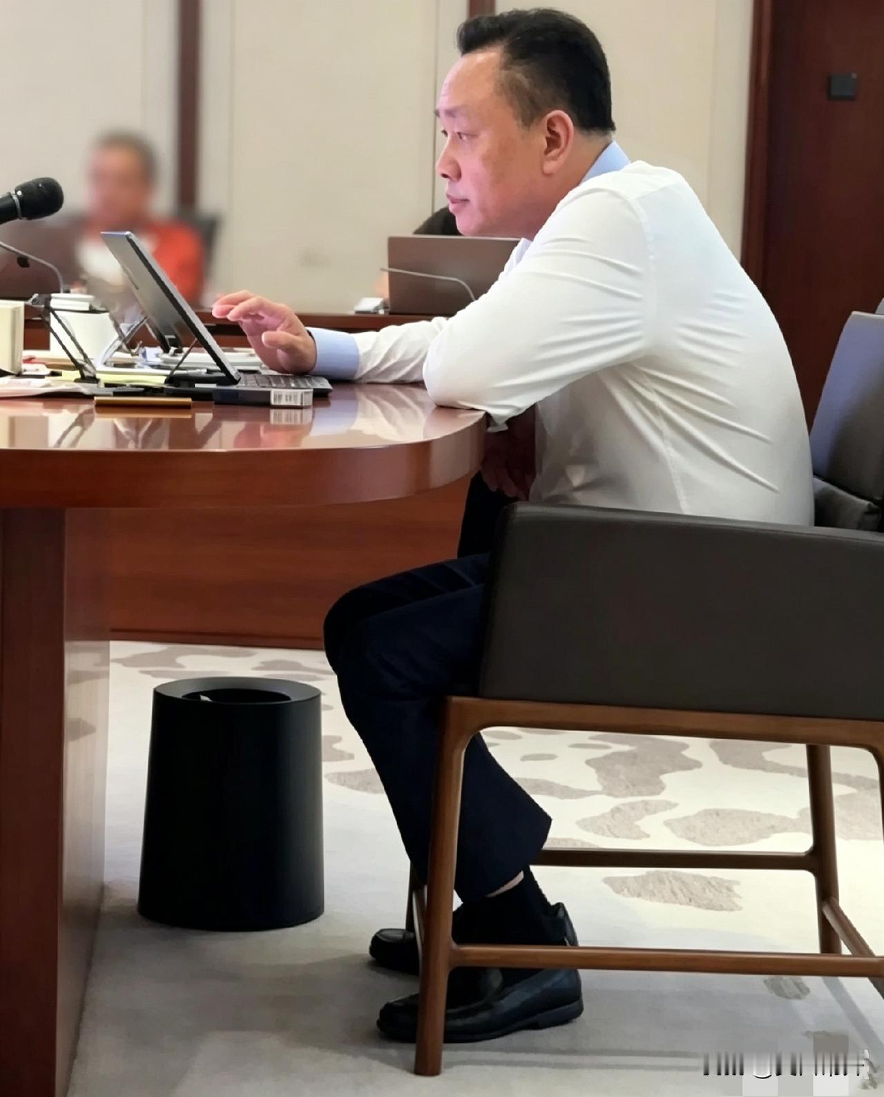 黄光裕在总部开会，脚下地毯上蜷着条狗，据说是他养的。