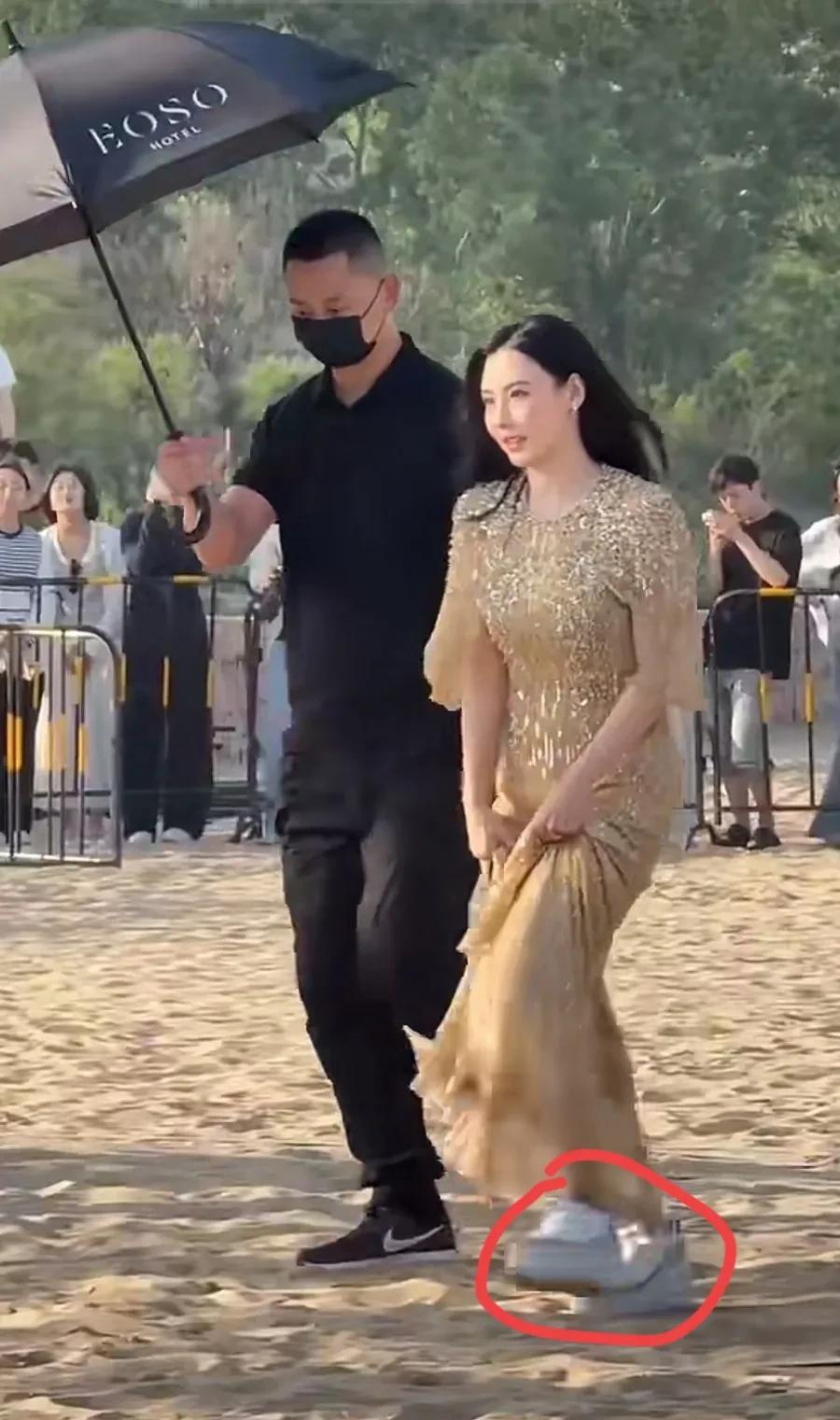 近日参加活动的张柏芝一身金色长裙亮相，由于活动现场是沙土地，女神不得不把长裙撩起