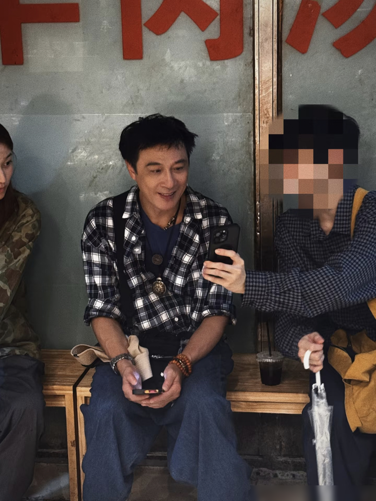 65岁吴镇宇，一个人蹲在成都街头吃小吃，连个拎包的都没有。被认出来就笑，合影来者不拒。格子衬衫配铆钉